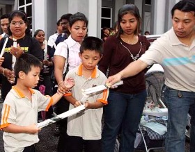 Picture: Helping hand: A senior parishioner helping young ones light candles before joining in the procession"