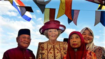 Afbeelding: Koningin Beatrix wordt verwelkomd door Pengarah Haji Mokti bin Mohammed Salleh (L), het dorpshoofd van het traditionele waterdorp Tamoi Tengah, en zijn familie."